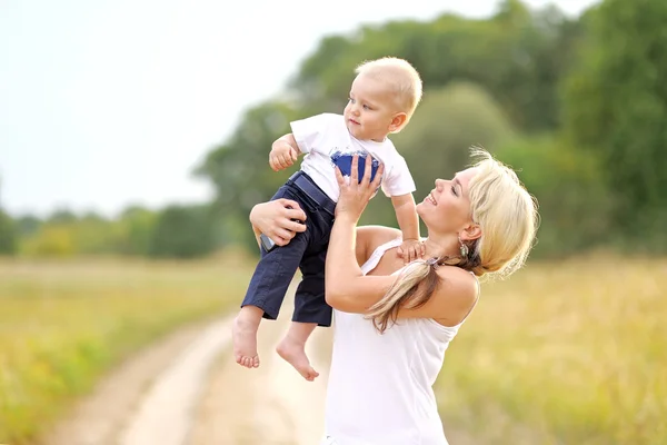 Glad mamma och baby son i sommar natur — Stockfoto