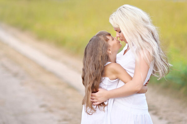 Young mother hugging her daughter in summer nature