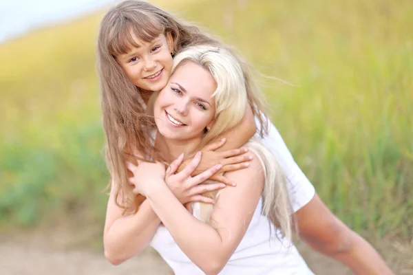 Молодая мать обнимает свою дочь летом на природе — стоковое фото