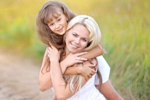 Young mother hugging her daughter in summer nature