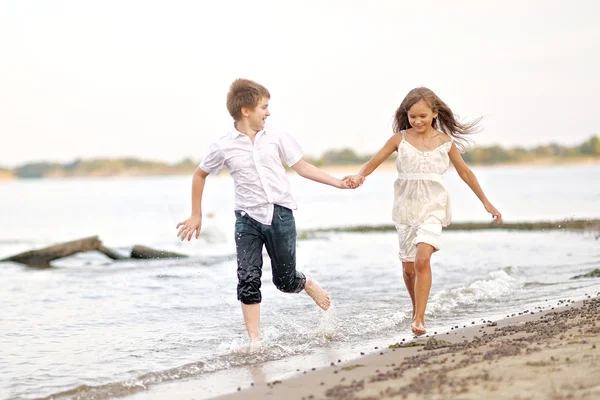 Porträt eines Jungen und eines Mädchens, die am Strand laufen — Stockfoto