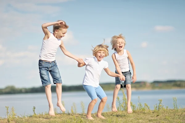 Drei Kinder spielen im Sommer auf Wiese — Stockfoto