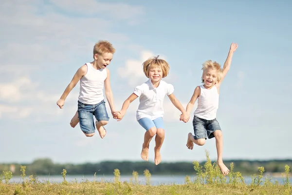 Trois enfants jouant sur la prairie en été — Photo