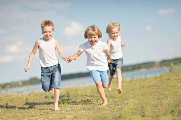 Tre barn leker på ängen i sommar — Stockfoto