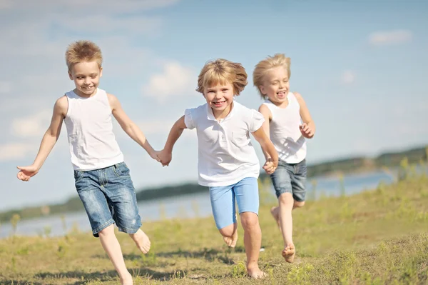 Drei Kinder spielen im Sommer auf Wiese — Stockfoto