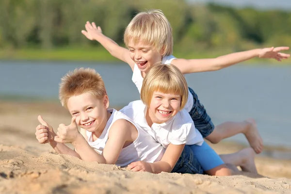 Porträt von drei Kindern, die am Strand spielen — Stockfoto