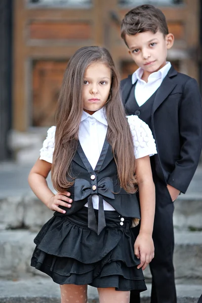 Porträtt av en pojke och en flicka i skolan kostym — Stockfoto