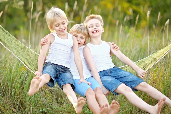 Three children playing on meadow in summer Stock Image