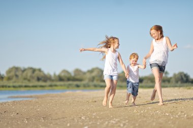 Yazın plajda oynayan üç çocuk.