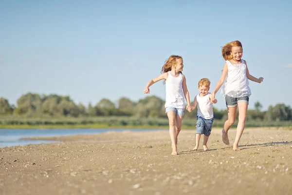 Drei Kinder spielen im Sommer am Strand — Stockfoto