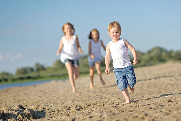 Tres niños jugando en la playa en verano —  Fotos de Stock