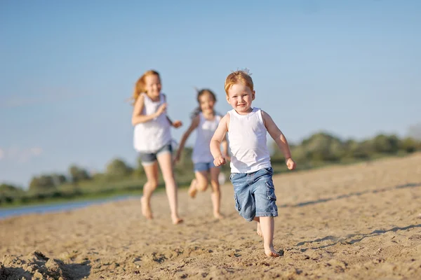 Drei Kinder spielen im Sommer am Strand — Stockfoto