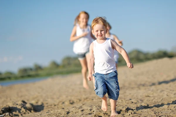 Três crianças brincando na praia no verão — Fotografia de Stock