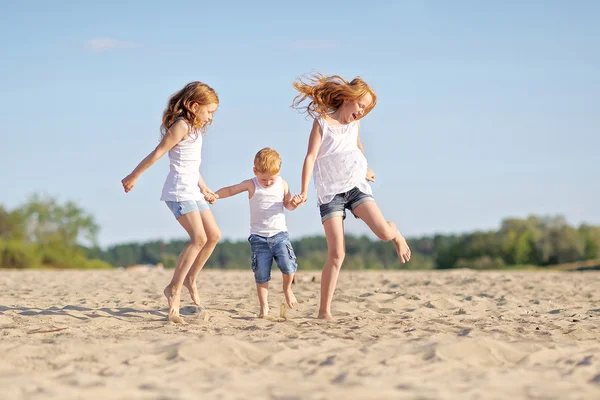 Drie kinderen spelen op het strand in de zomer — Stockfoto