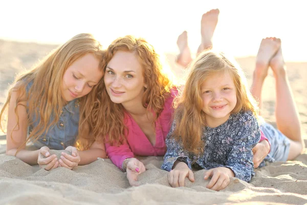 Moeder en haar twee dochters op het strand in de zomer — Stockfoto