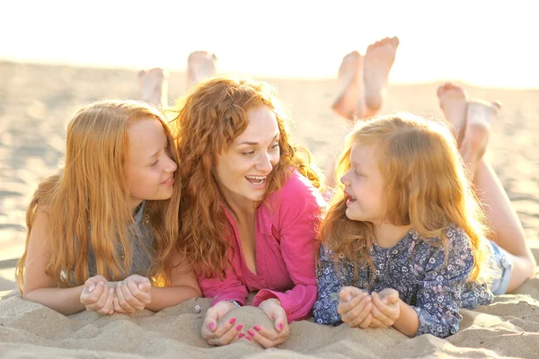 Moeder en haar twee dochters op het strand in de zomer — Stockfoto