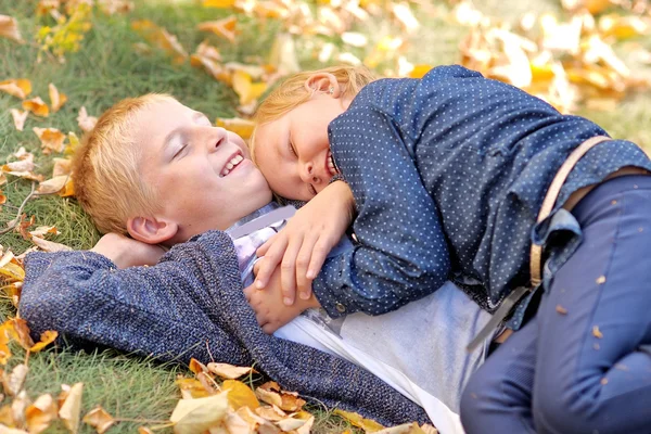 Portrait of brother and sister in autumn leaves — Stock Photo, Image