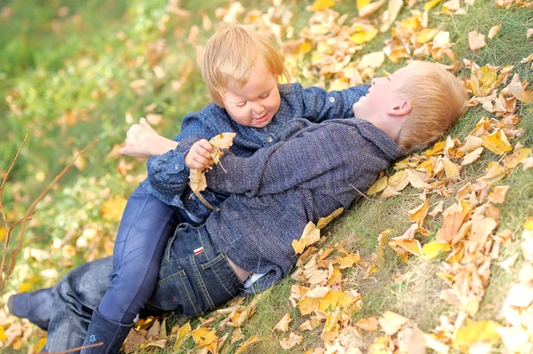 Porträtt av bror och syster i höstlöv — Stockfoto