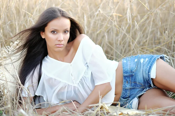 Mooie elegante brunette meisje in een veld — Stockfoto