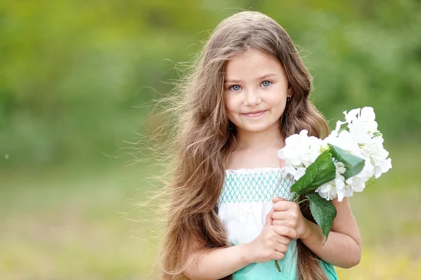 Porträtt av en vacker liten flicka med blommor — Stockfoto