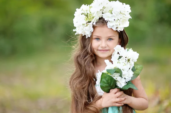 Portret van een mooi klein meisje met bloemen — Stockfoto