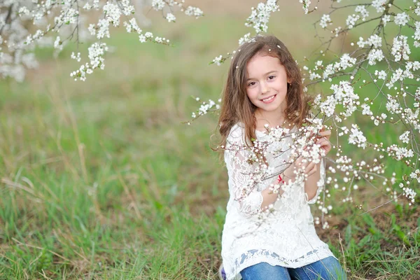 Porträtt av en vacker liten flicka med blommor — Stockfoto