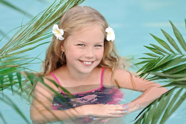 Porträtt av liten flicka i tropisk stil i en pool — Stockfoto