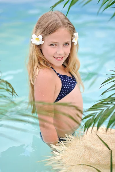 Portrait of little girl in tropical style in a swimming pool — Stock Photo, Image