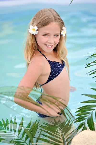 Portrait of little girl in tropical style in a swimming pool — Stock Photo, Image