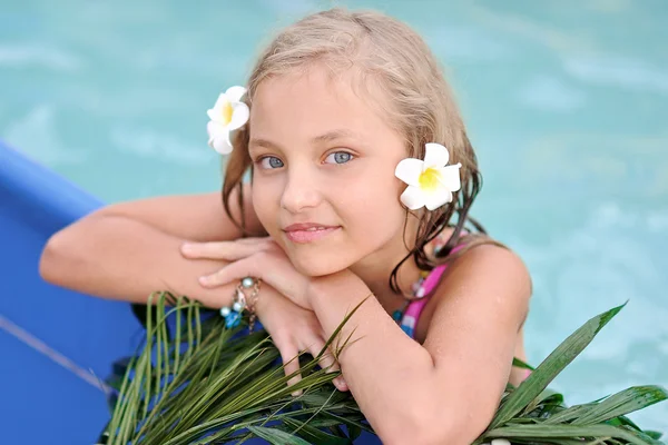 Portrait of little girl in tropical style in a swimming pool — Stock Photo, Image