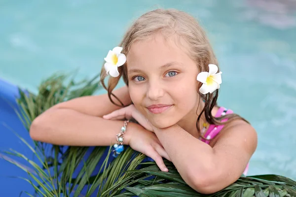 Portrait of little girl in tropical style in a swimming pool — Stock Photo, Image