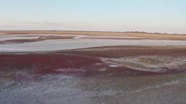 Güzel bir göl kenarında kumlu bataklık ve renkli bir gün batımı.