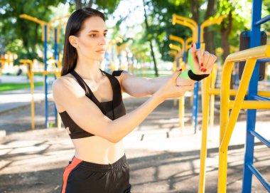 Kineziyolojik bantlı bir kadın spor alanında esniyor..