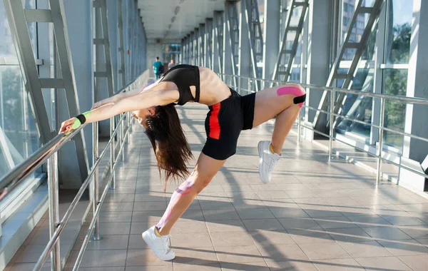 Mujer con cinta de kinesiología practicando gimnasia en interiores. — Foto de Stock