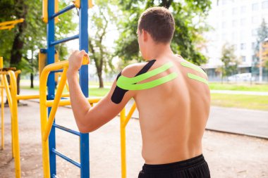 Spor sahasında poz veren elastik bantlarla vücut geliştirici.