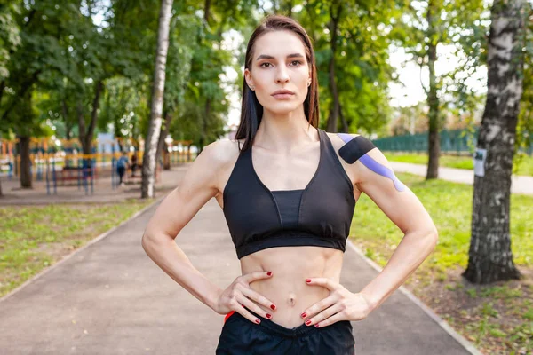 Mujer en forma con cinta cinesiológica posando al aire libre. — Foto de Stock