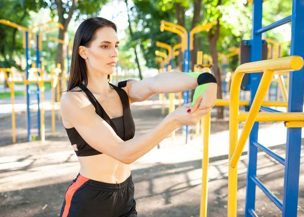 Mujer con cinta cinesiológica estirándose en campo deportivo. — Foto de Stock