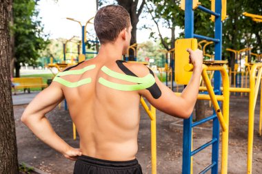 Spor sahasında poz veren elastik bantlarla vücut geliştirici.