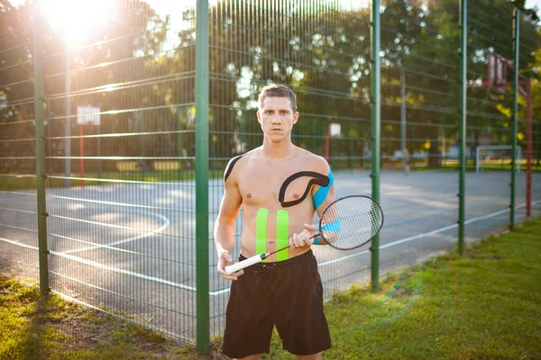 Atleta com cinesiologia gravando posando com raquete ao ar livre. — Fotografia de Stock