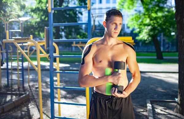 Spor sahasında poz veren kinezyolojik bantlı bir sporcu.