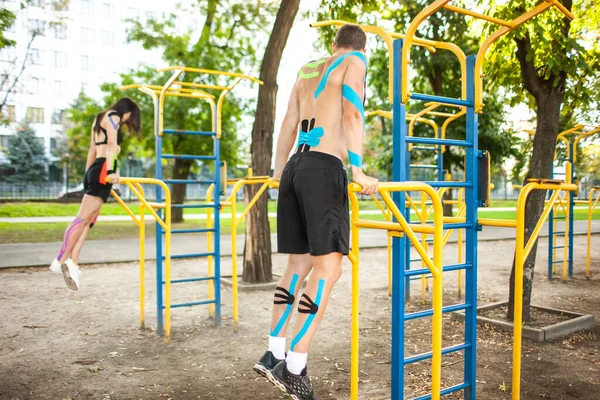 Koppel met kinesiologische elastische tapingtraining op sportterrein. — Stockfoto