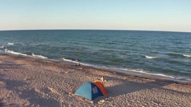 Akşam ışığında deniz kenarında parlak bir çadır.