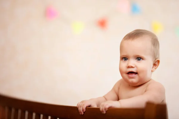 Nu feliz rindo bebê de pé no berço. — Fotografia de Stock