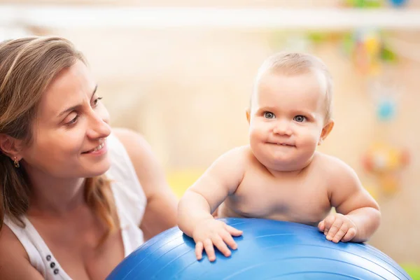 Treinamento do bebê com bola de ginástica com a mãe em casa. — Fotografia de Stock