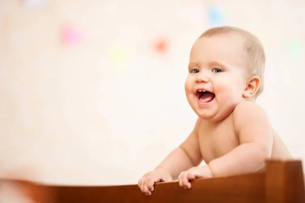 Nudo felice ridendo bambino in piedi in culla. — Foto Stock