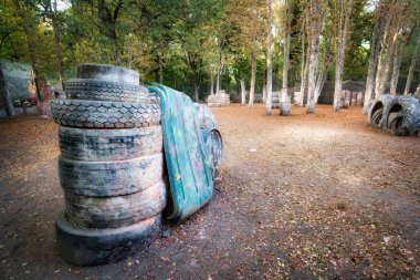 Paintball tabanında eski paslı fıçılar ve hasarlı lastikler.