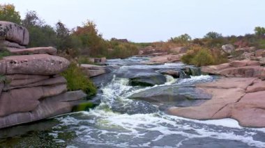 Pürüzsüz ve karanlık taşların arasında küçük parlak bir dere akıyor.