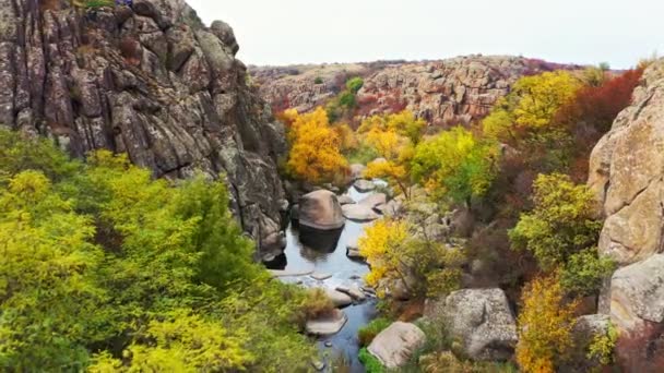 En pittoresk bäck rinner i Aktovsky Canyon, omgiven av höstträd och stora stenblock — Stockvideo