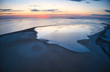 Parlak bir göl ve renkli bir günbatımında alışılmadık adalar