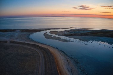 Parlak bir göl ve renkli bir günbatımında alışılmadık adalar